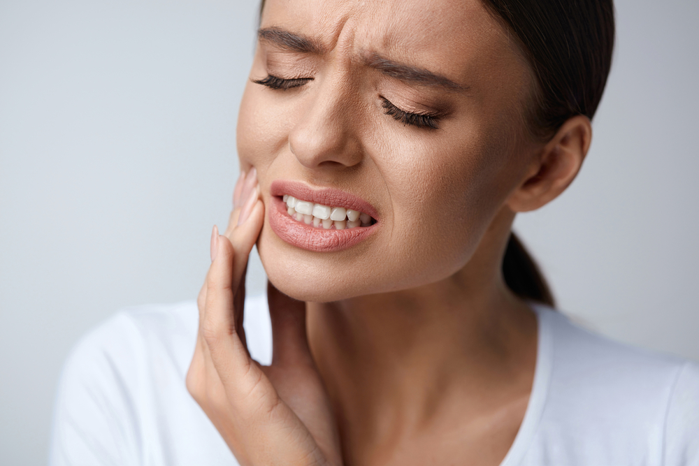 young lady in dental pain holding her cheek